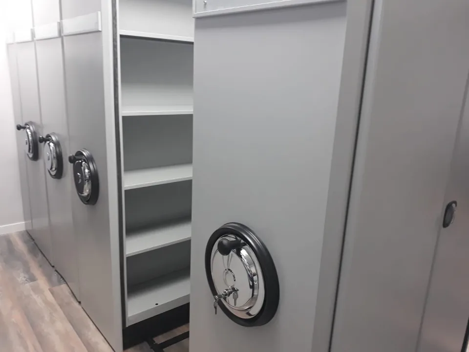 Compact archive installed in RAL 7035 light gray, one bay rolled open showing four shelf levels