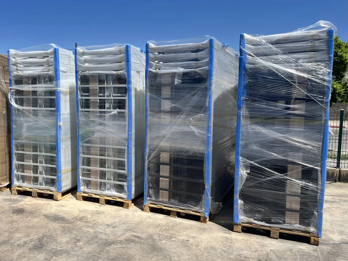 Four bunk bed pallets stretch wrapped over blue corner protectors, standing on wooden pallets