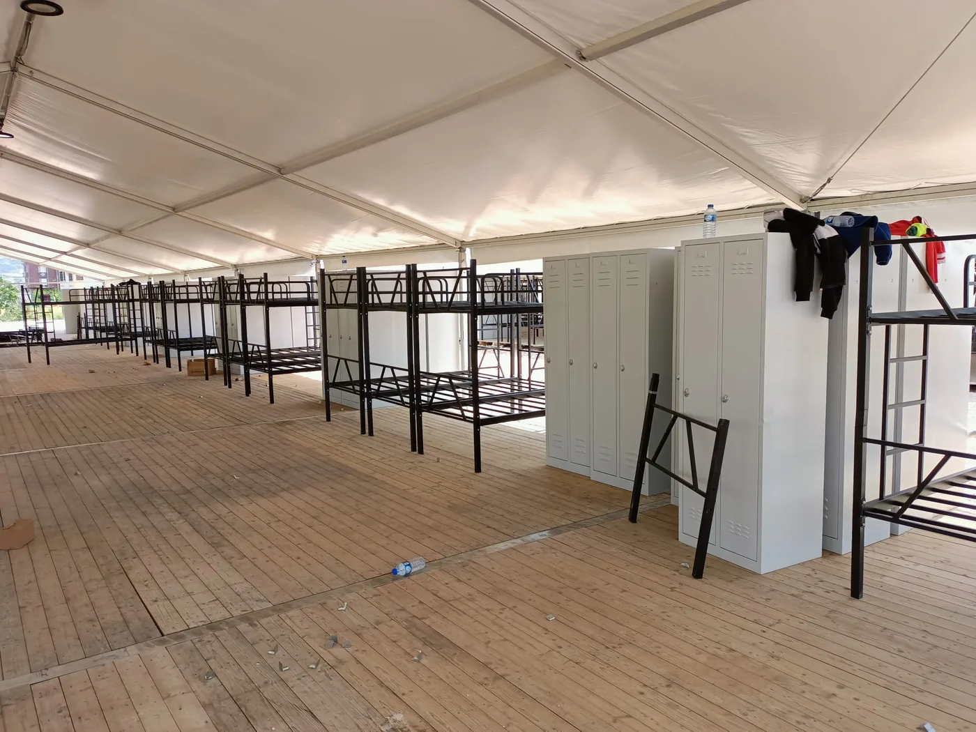 Assembled bunk beds and a bank of gray steel lockers inside a tent