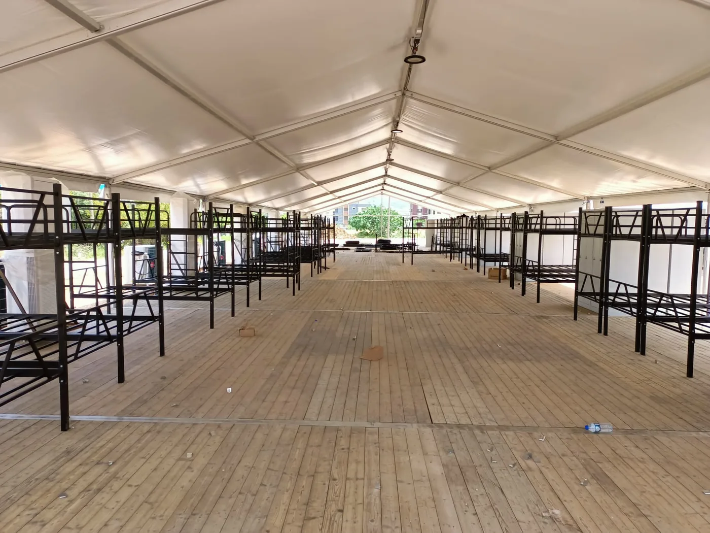 Rows of assembled bunk beds down both sides of a tent