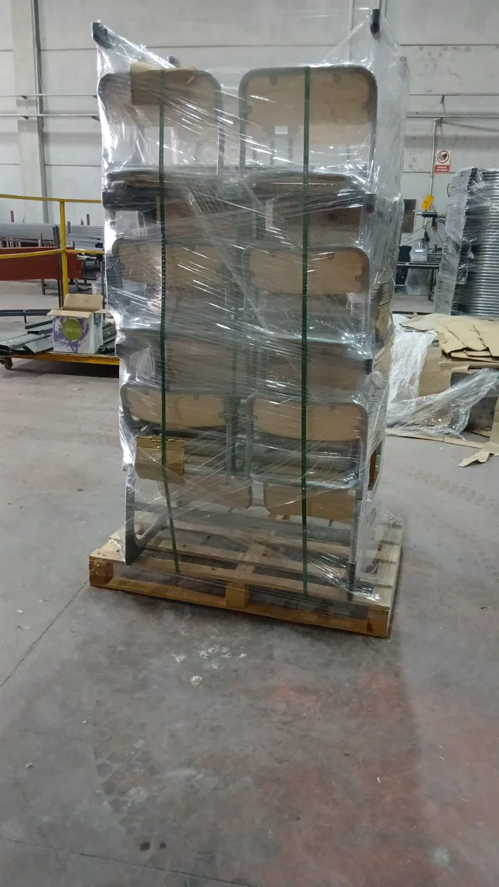 Pallet of classic school chairs with wooden seats, stacked in two columns and stretch wrapped