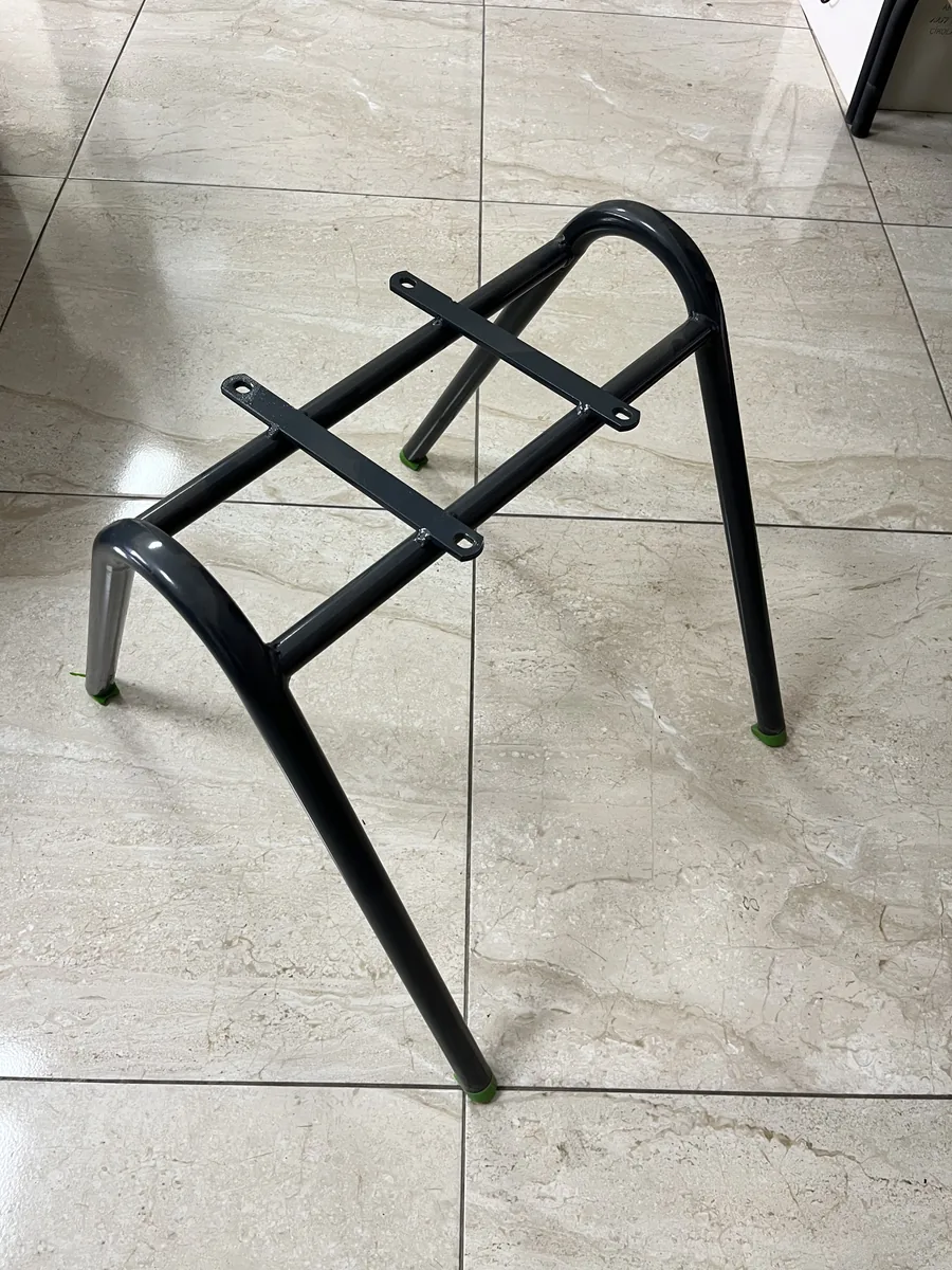 Bare plastic school chair frame, round steel legs with two flat mounting straps and green foot caps