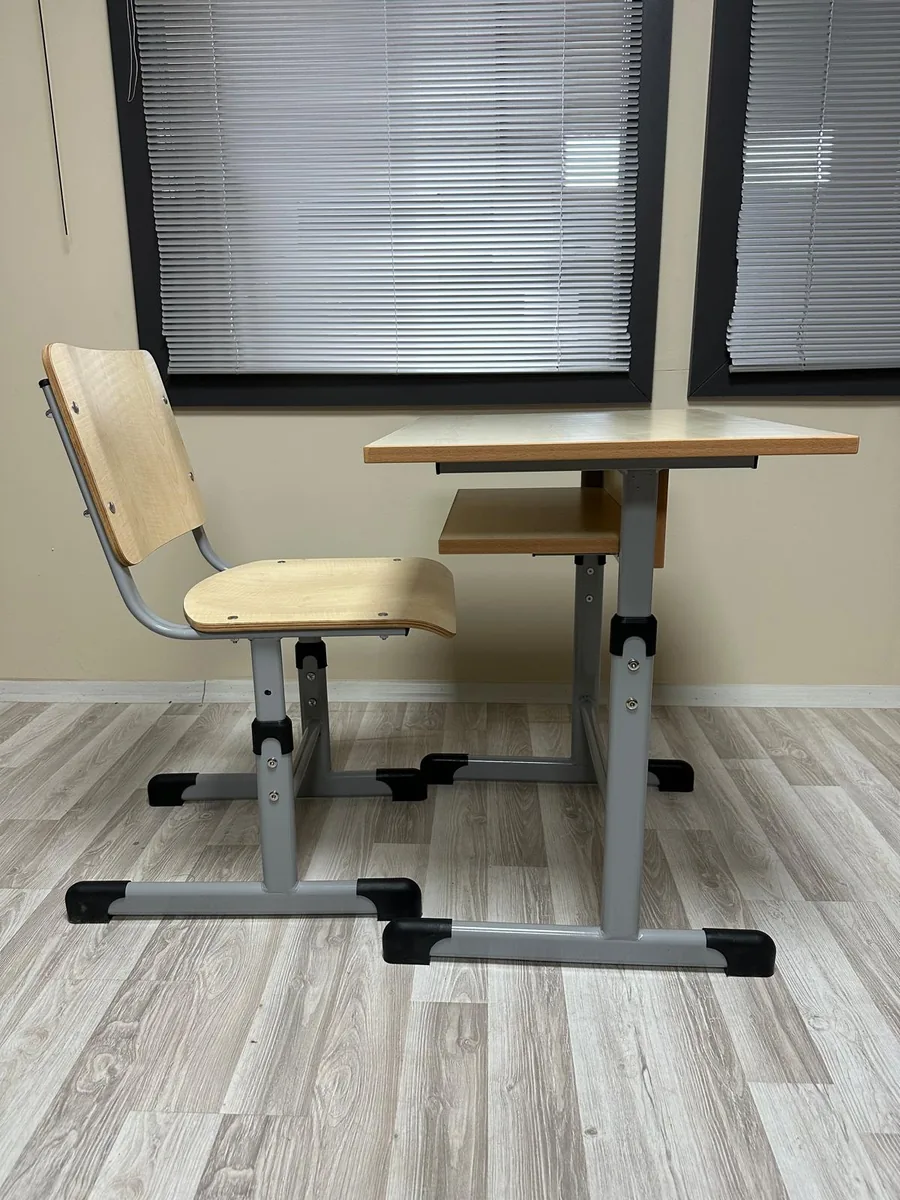 Height adjustable student desk and seat standing in a room, seen from the side