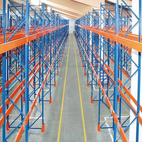 Aisle of tall blue and orange heavy duty pallet racking, uprights on foot plates anchored to the floor